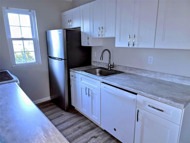 kitchen featuring white cabinetry, sink, white appliances, and wood-type flooring