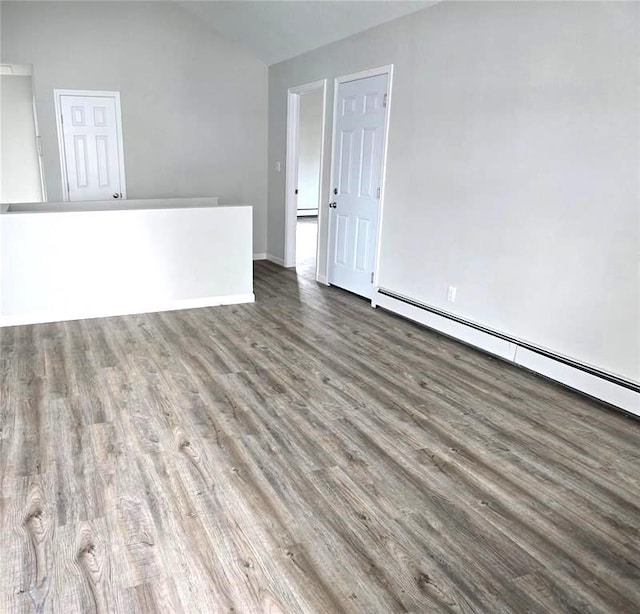 empty room featuring baseboard heating and dark hardwood / wood-style flooring