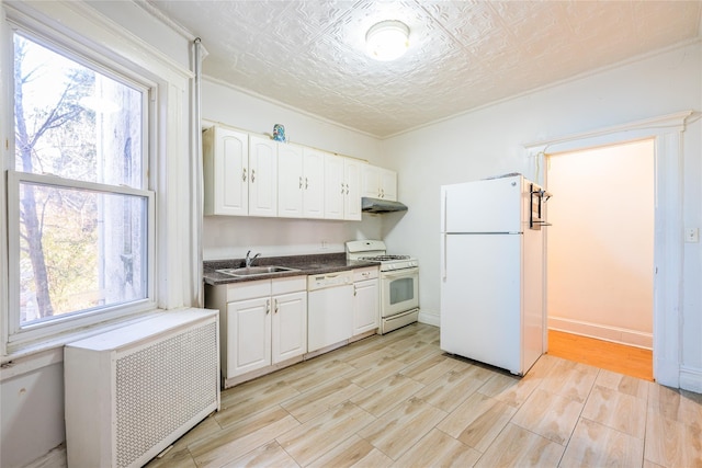 kitchen with white cabinetry, white appliances, radiator heating unit, and sink