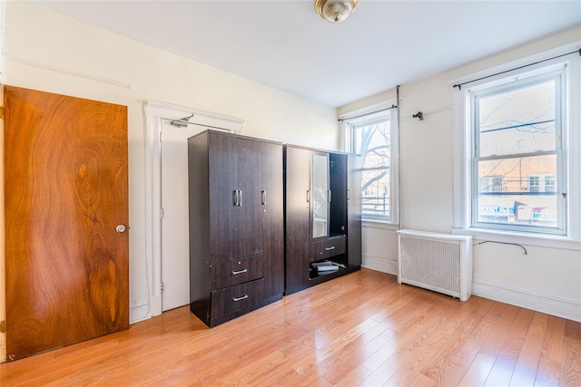 unfurnished bedroom featuring light hardwood / wood-style flooring and radiator heating unit