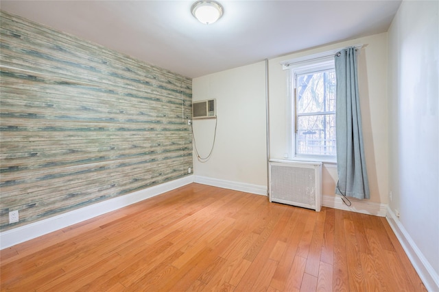 spare room featuring radiator, light hardwood / wood-style flooring, and a wall mounted AC