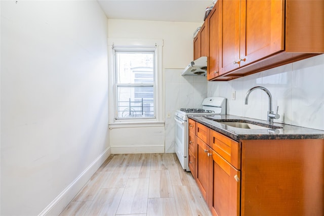 kitchen featuring sink, decorative backsplash, dark stone counters, white gas stove, and light wood-type flooring