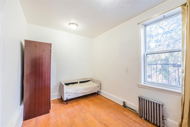 unfurnished bedroom featuring multiple windows, radiator heating unit, and light wood-type flooring