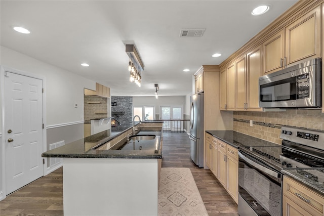 kitchen with sink, backsplash, dark hardwood / wood-style flooring, stainless steel appliances, and a center island with sink