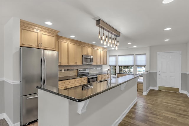 kitchen featuring appliances with stainless steel finishes, a kitchen island with sink, sink, and hanging light fixtures