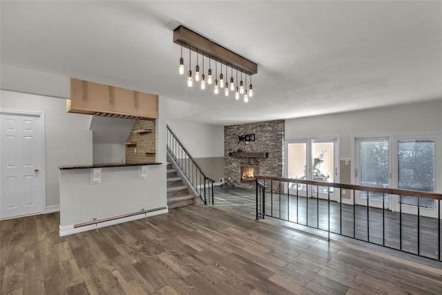 unfurnished living room featuring a stone fireplace and dark hardwood / wood-style floors