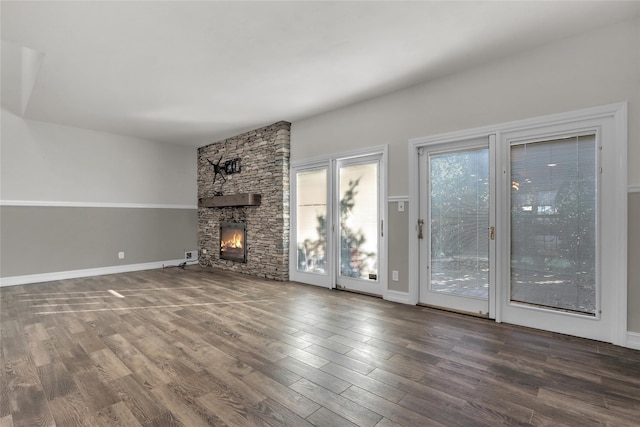 unfurnished living room with hardwood / wood-style flooring and a stone fireplace