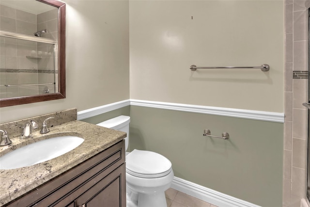 bathroom featuring tile patterned floors, toilet, a shower with shower door, and vanity