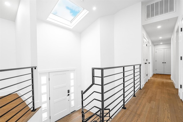 corridor with wood-type flooring and a skylight