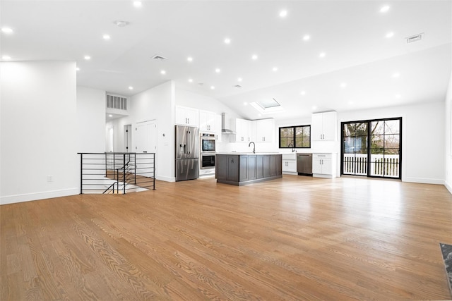 unfurnished living room with vaulted ceiling, sink, and light hardwood / wood-style flooring