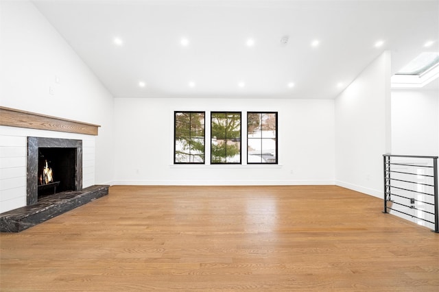 unfurnished living room featuring lofted ceiling, a fireplace, and light wood-type flooring