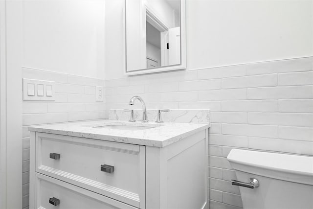 bathroom with vanity, tile walls, and toilet