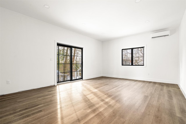 spare room featuring hardwood / wood-style flooring, a wealth of natural light, and a wall mounted AC