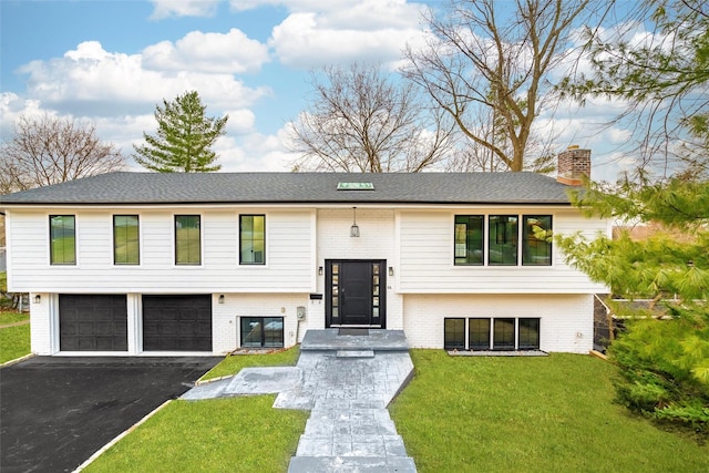 bi-level home featuring a garage and a front lawn