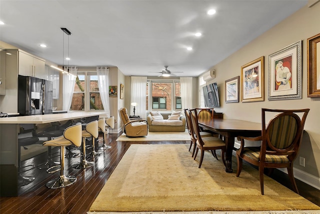 dining room featuring ceiling fan, dark hardwood / wood-style floors, and a wall unit AC