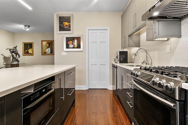 kitchen with range hood, backsplash, wall oven, gas stove, and dark wood-type flooring