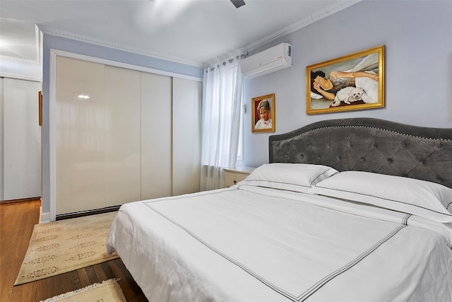 bedroom with a wall mounted air conditioner, ornamental molding, dark hardwood / wood-style floors, a closet, and ceiling fan