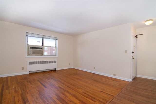 spare room with dark hardwood / wood-style floors and radiator heating unit