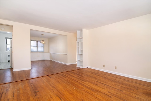 unfurnished room featuring an inviting chandelier, radiator heating unit, and wood-type flooring