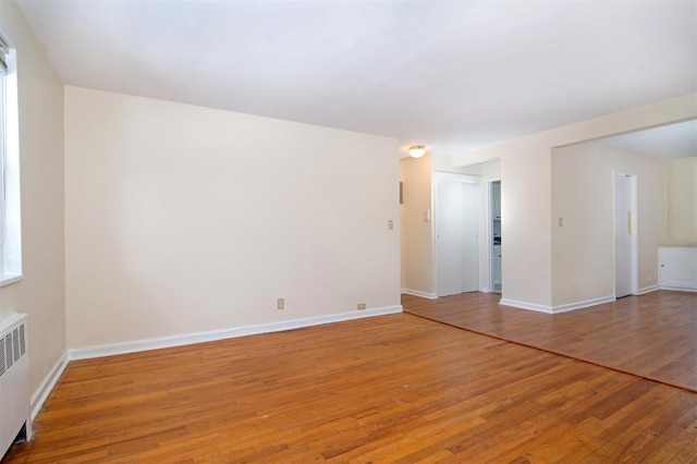 empty room featuring radiator and hardwood / wood-style floors