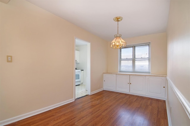 empty room with hardwood / wood-style flooring and an inviting chandelier