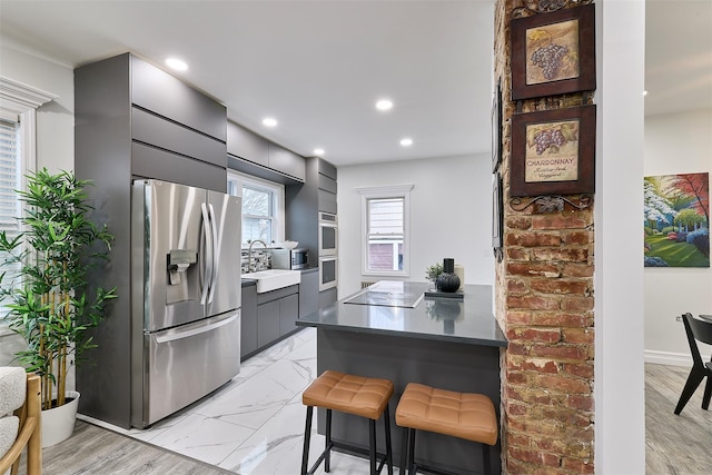 kitchen with sink, a kitchen breakfast bar, stainless steel refrigerator with ice dispenser, black electric cooktop, and kitchen peninsula