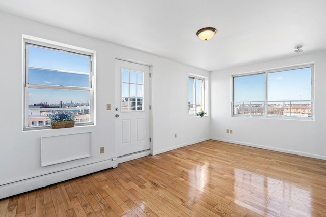 entrance foyer featuring a healthy amount of sunlight, light hardwood / wood-style floors, and a baseboard heating unit