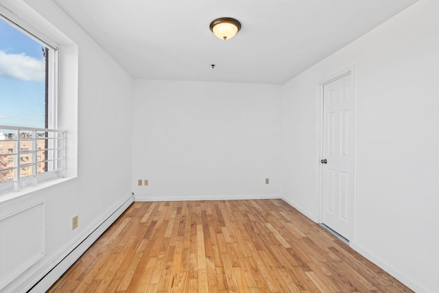 unfurnished room featuring a baseboard heating unit and light hardwood / wood-style flooring