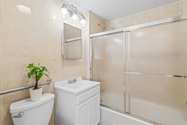 full bathroom featuring vanity, tile walls, shower / bath combination with glass door, and toilet