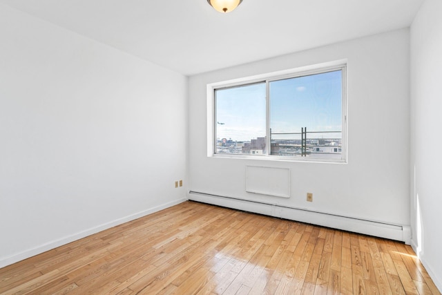 spare room featuring a baseboard radiator and light wood-type flooring