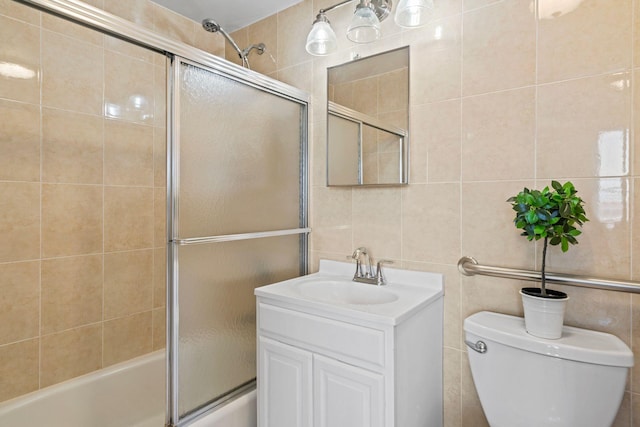 full bathroom featuring vanity, combined bath / shower with glass door, tile walls, and toilet