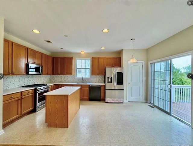 kitchen with sink, a center island, hanging light fixtures, appliances with stainless steel finishes, and backsplash