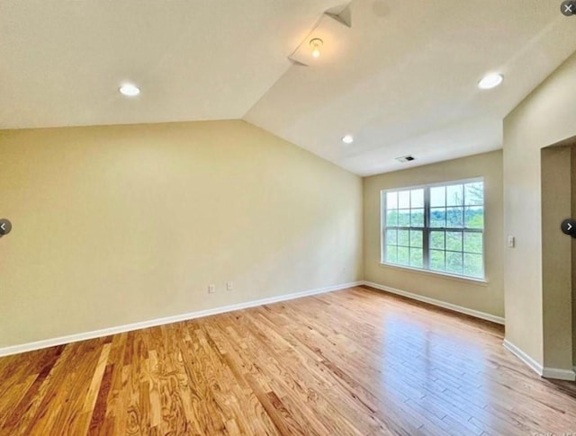 spare room featuring vaulted ceiling and light hardwood / wood-style floors