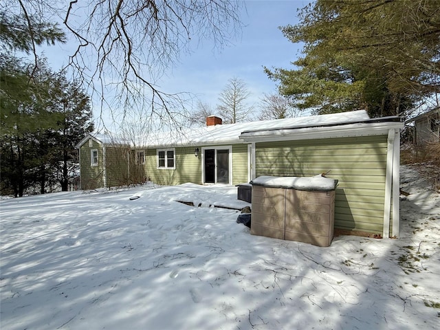 snow covered back of property featuring a chimney