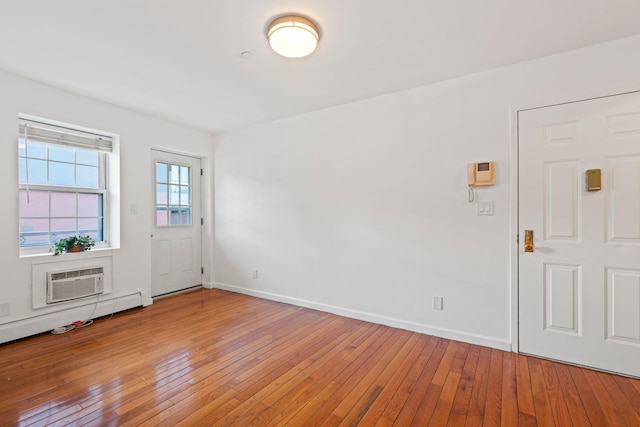 entrance foyer with hardwood / wood-style flooring, a baseboard heating unit, and a wall mounted air conditioner