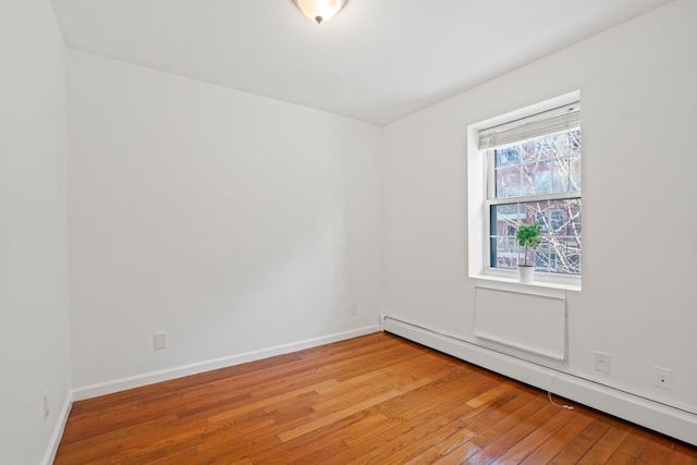 spare room with baseboard heating and wood-type flooring