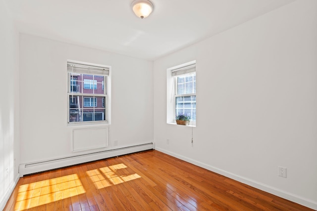 empty room featuring light wood-type flooring and baseboard heating