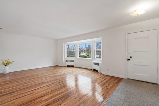 interior space with radiator heating unit and light hardwood / wood-style floors