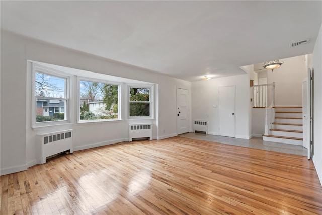 unfurnished living room featuring light hardwood / wood-style flooring, radiator heating unit, and a healthy amount of sunlight