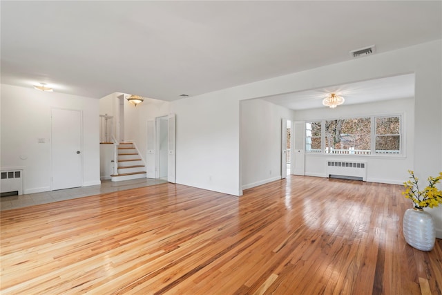 unfurnished living room featuring radiator and light hardwood / wood-style flooring