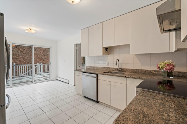 kitchen featuring appliances with stainless steel finishes, sink, backsplash, dark stone counters, and baseboard heating