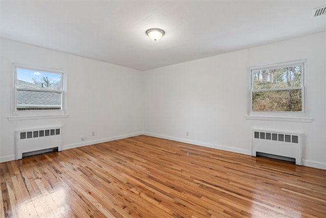 unfurnished living room featuring radiator heating unit and light hardwood / wood-style flooring