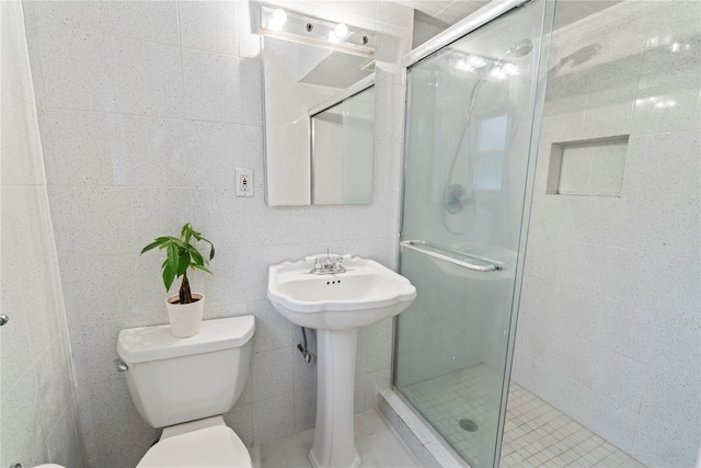 bathroom featuring toilet, sink, and a shower with shower door