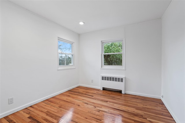 empty room with a healthy amount of sunlight, radiator, and light hardwood / wood-style floors