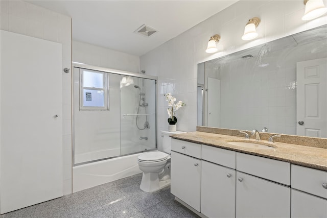 full bathroom with enclosed tub / shower combo, vanity, and toilet