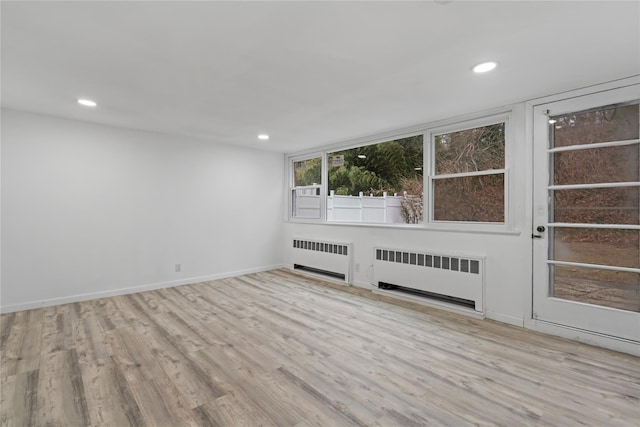 unfurnished room featuring radiator and light hardwood / wood-style floors