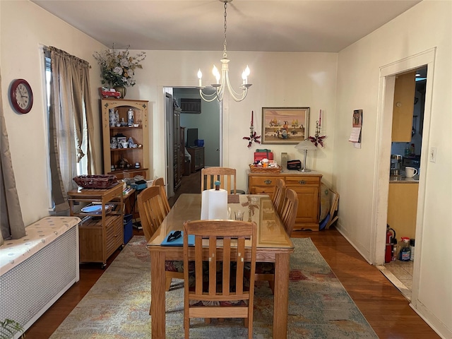 dining room with baseboards, a notable chandelier, dark wood finished floors, and radiator heating unit