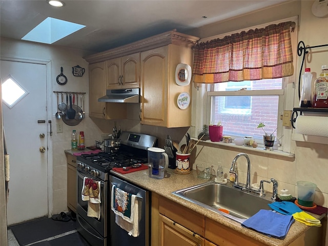 kitchen featuring a skylight, stainless steel appliances, light countertops, a sink, and under cabinet range hood