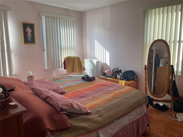 bedroom with radiator and wood finished floors