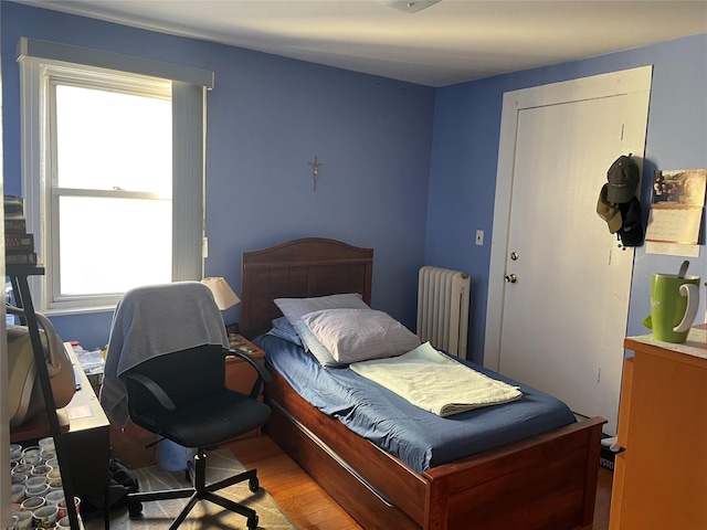 bedroom with radiator heating unit and light wood-style flooring